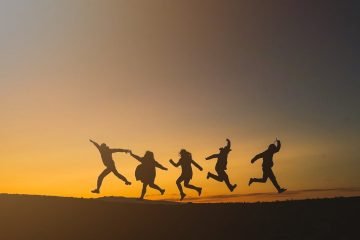 unrecognizable happy people jumping in sunset